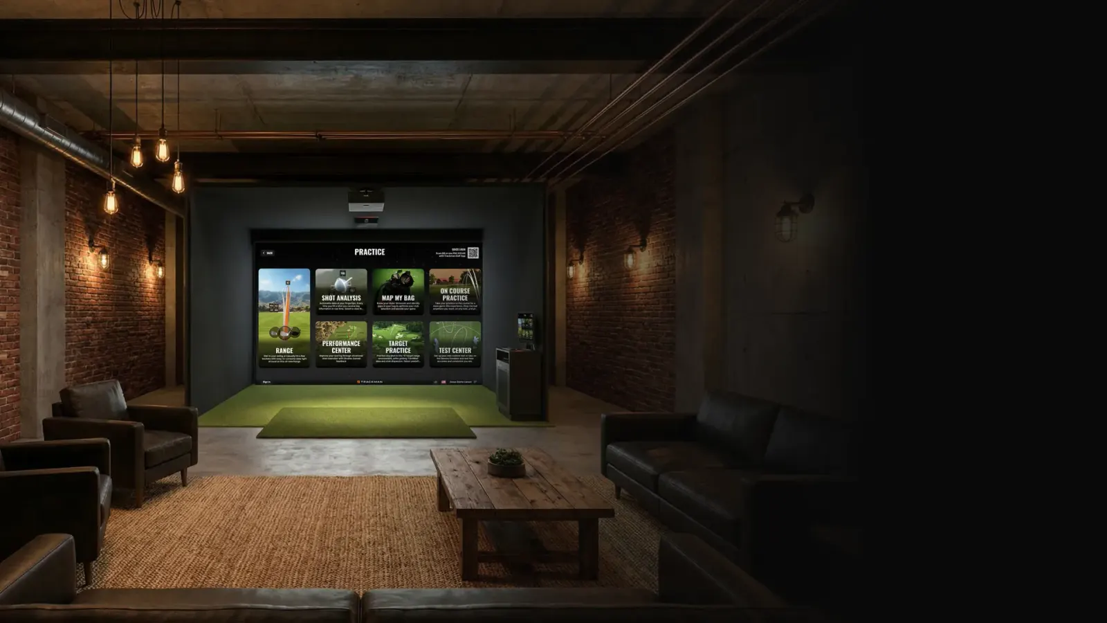 An indoor golf simulator bay with a TrackMan iO unit mounted on the ceiling and a course on the screen